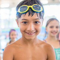 Young boy with swim goggles on his head in swimming pool