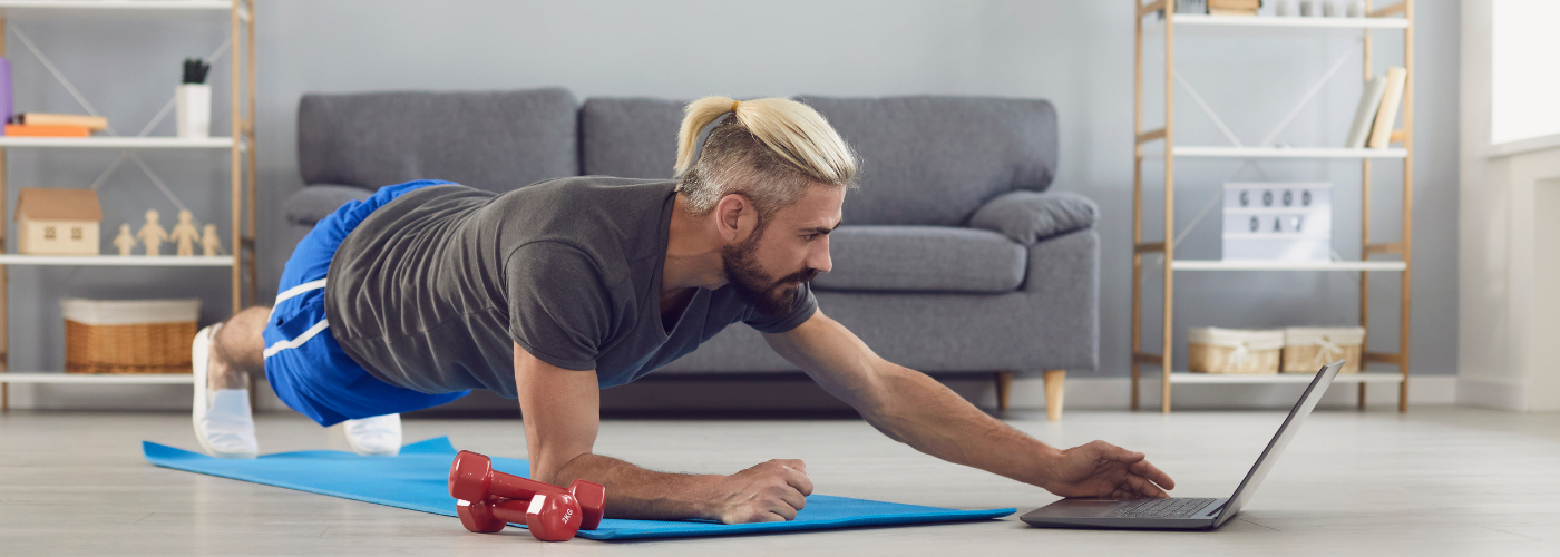 adult doing a plank in front of laptop