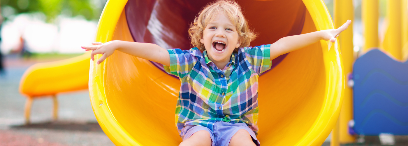 Little boy coming down a yellow slide