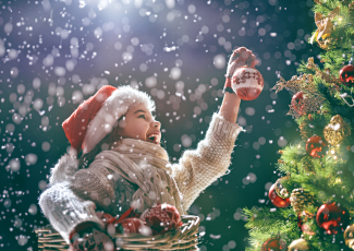 little girl placing ornaments on tree