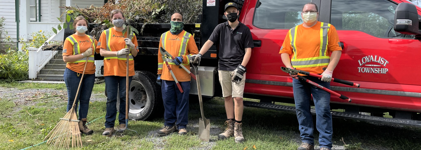 volunteers in high-viz shirts standing in a line with garden toolsols