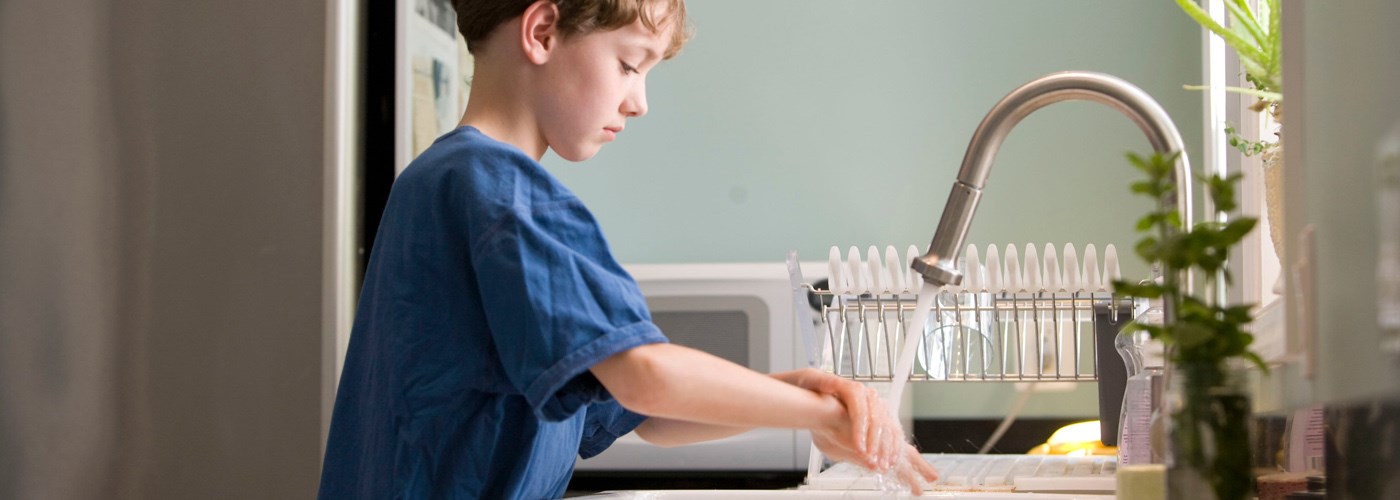 Young boy washing his hands under kitchen faucet