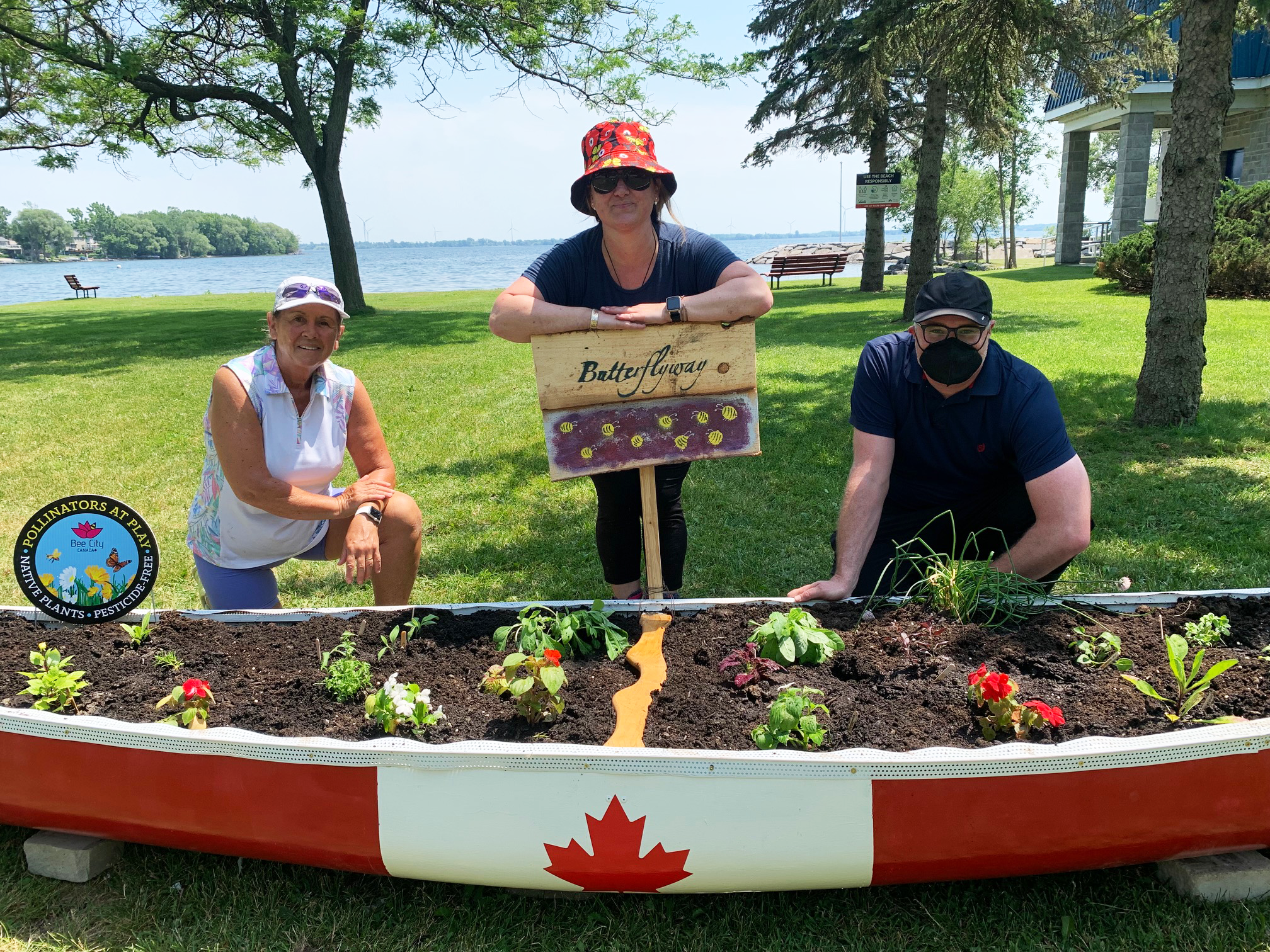 Bath Gardening Club members and Loyalist Township's Climate Action Coordinator installing the pollinator garden within a canoe painted like the Canadian flag.