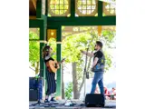 Two peoples singing and the one of the left is playing guitar.