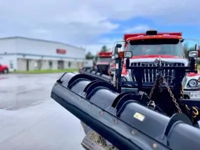 red snow plow parked on wet paving