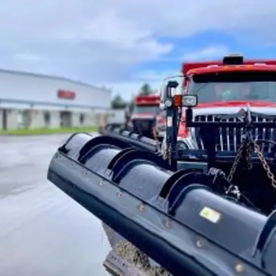 red snow plow parked on wet paving