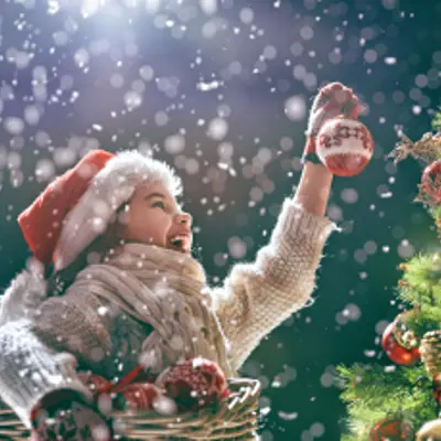 little girl placing ornaments on tree
