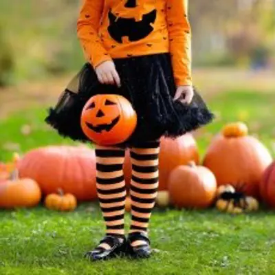 Little girl in halloween costume with pumpkins behind